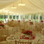 Wedding Marquee with glazing, tables, chairs, lighting, flowers and clear gables and walls