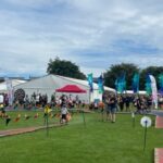 Top field of Cowal Highland Gathering with marquees, families and activities including a large dartboard and cycling.