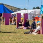 Butefest 2022, marquee in a field on a bright day with people lying on the grass chatting and eating ice cream.
