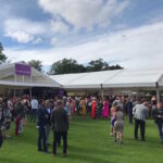 Marquees in Hamilton Park on a bright July day with people dressed in suits and dresses.