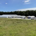 A filming village with marquees, vans and portable toilets in the Scottish countryside.