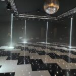 Black and white LED dance floor illuminated by disco ball, spotlights and small LED lights.