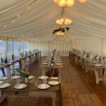 Soft festoon lighting and globe chandeliers in harmony in a wedding marquee