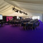 Purple carpeted furnished marquee for Hamilton Park Racecourse Showcase awards event with solid opening glazed windows.