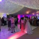 Pea lamp roof canopy over an LED dancefloor with LED coloured uplighters in a wedding marquee