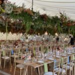 Autumn wedding bringing the outside in with hanging floral decorations on a truss and festoon lighting